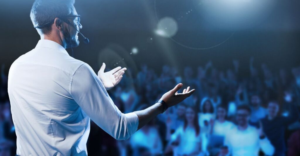 a person speaking in front of a crowd - how to plan a conference
